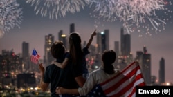 Una familia contempla los fuegos artificiales sobre un paisaje urbano. 