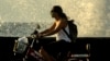 Una mujer se traslada en bicicleta por el Malecón habanero en medio de la pandemia de coronavirus. (AP/Ramon Espinosa)