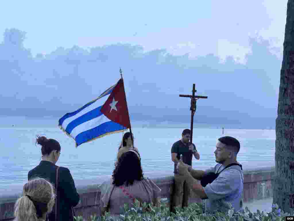 Orando frente al mar, con la bandera cubana y la cruz, al finalizar el Via Crucis.