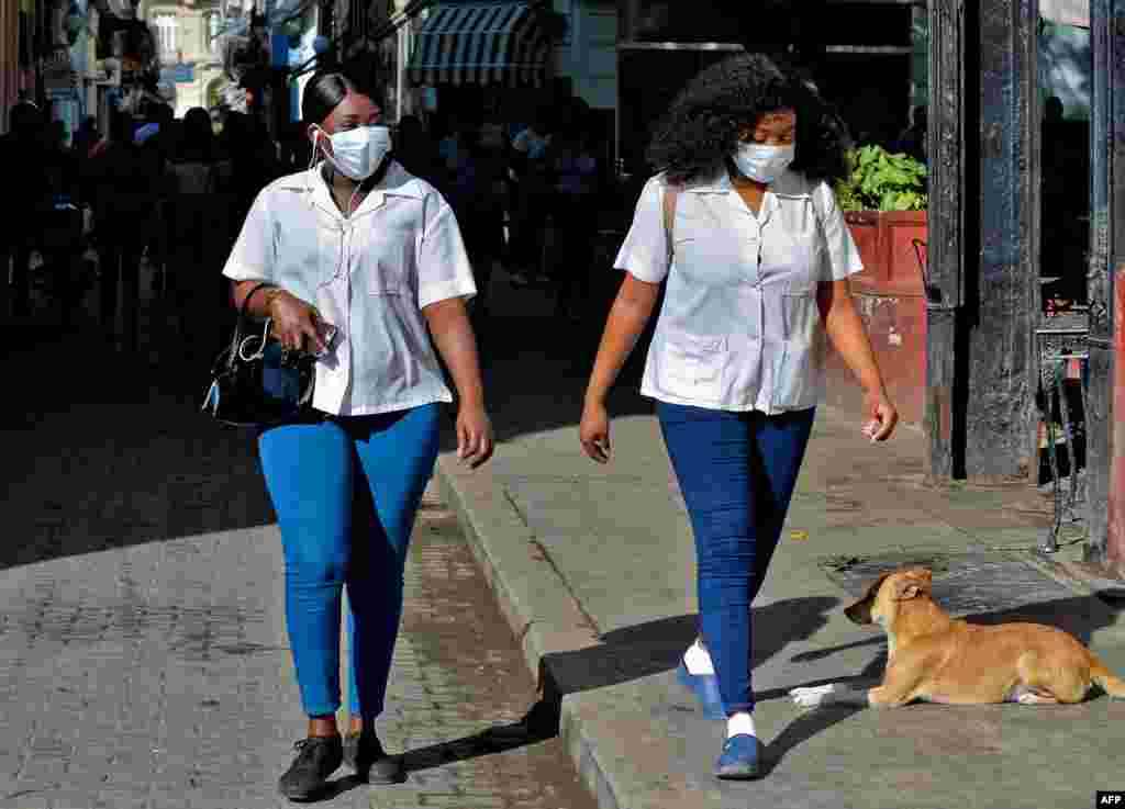 Las mujeres usan máscaras faciales mientras caminan por las calles de La Habana