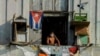Un hombre se asoma a un balcón, en La Habana, con una máscara para protegerse del coronavirus. (Foto: Yamil Lage/AFP).